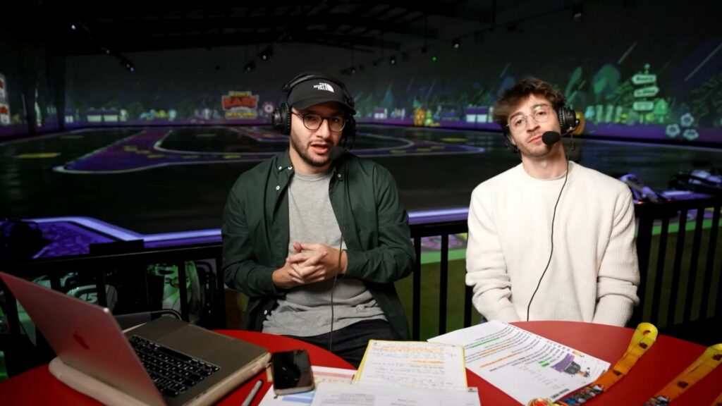 The two casters with headsets at their desk overlooking the BattleKart Dijon arena